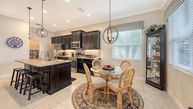 kitchen with light tile patterned floors, separate washer and dryer, dark brown cabinetry, and appliances with stainless steel finishes