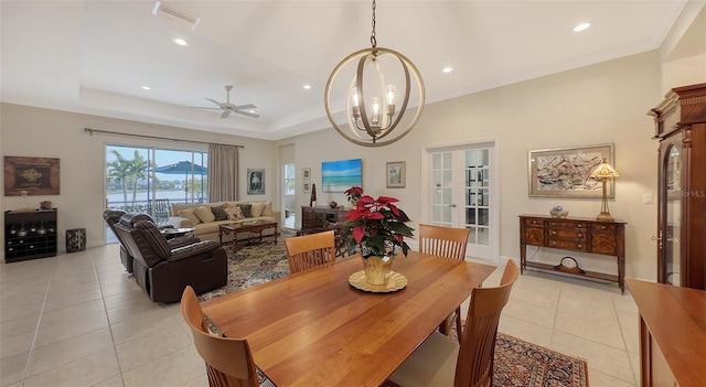 dining space featuring ceiling fan with notable chandelier, light tile patterned flooring, and a raised ceiling