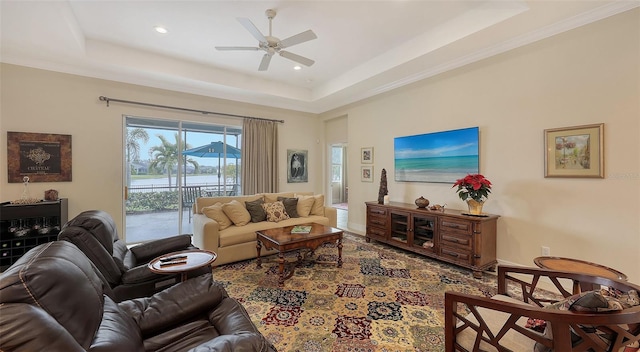 living room featuring ceiling fan, a raised ceiling, and ornamental molding