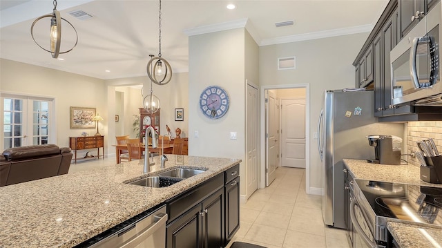 kitchen featuring appliances with stainless steel finishes, light stone counters, sink, light tile patterned floors, and decorative light fixtures