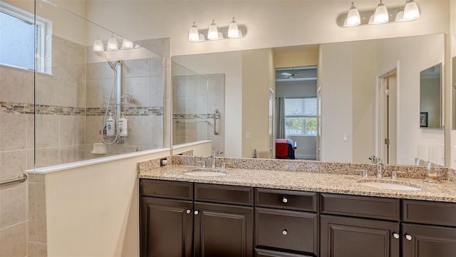 bathroom with a tile shower, ceiling fan, and vanity