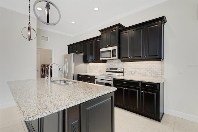 13789 Old Creek Ct, Parrish, FL 34219 - kitchen featuring washer and dryer, appliances with stainless steel finishes, an island with sink, backsplash, and dark cabinets