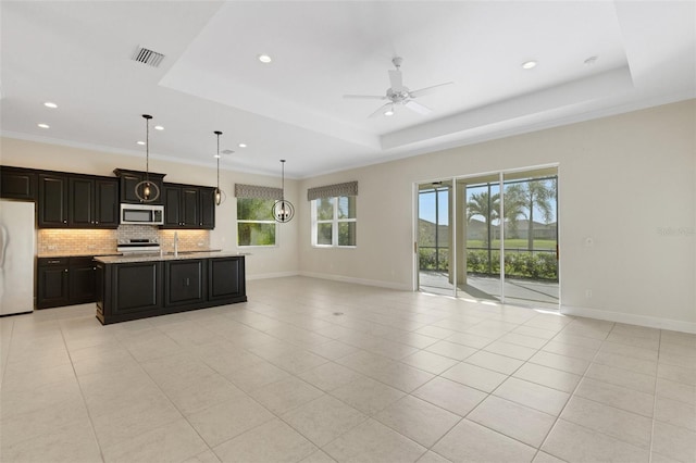 13789 Old Creek Ct, Parrish, FL 34219 - kitchen with appliances with stainless steel finishes, open floor plan, decorative backsplash, a ceiling fan, and a raised ceiling