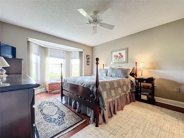 bedroom with ceiling fan, wood-type flooring, and a textured ceiling