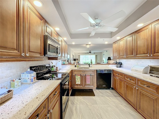 kitchen featuring black appliances, a raised ceiling, light stone countertops, and sink