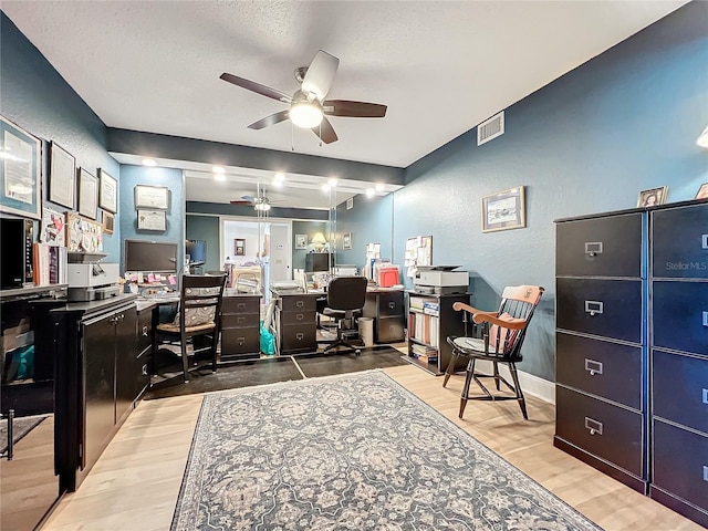 home office with ceiling fan, hardwood / wood-style floors, beamed ceiling, and a textured ceiling