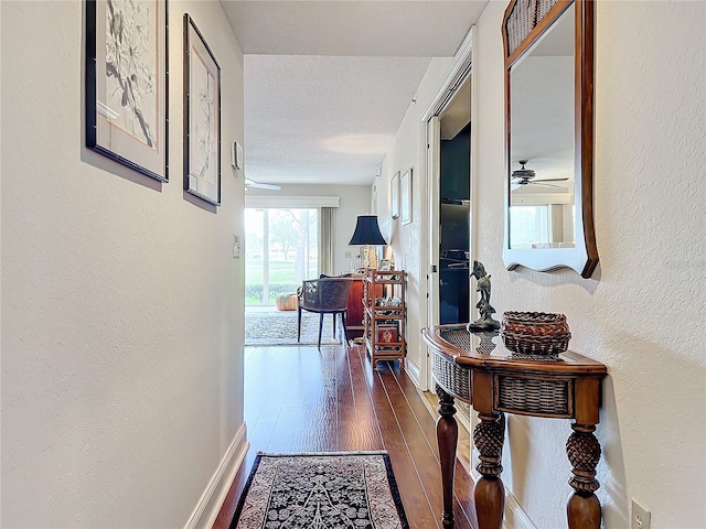 hallway with dark hardwood / wood-style floors and a textured ceiling