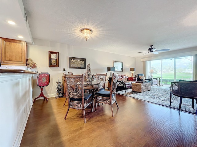 dining space with ceiling fan, wood-type flooring, and a textured ceiling