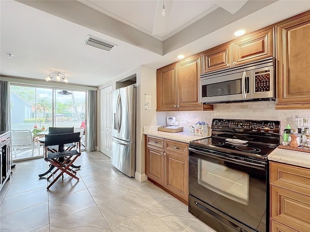 kitchen with backsplash, light stone counters, stainless steel appliances, crown molding, and light tile patterned flooring