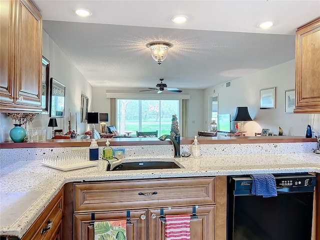 kitchen featuring ceiling fan, dishwasher, light stone countertops, and sink