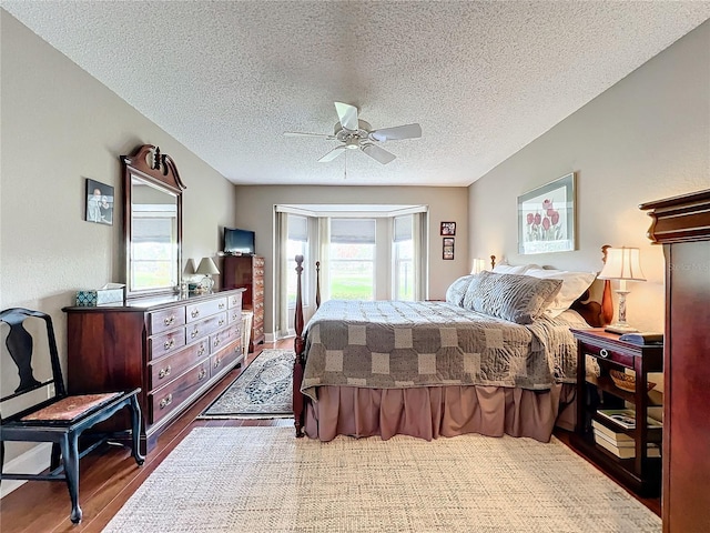 bedroom with ceiling fan, wood-type flooring, and a textured ceiling