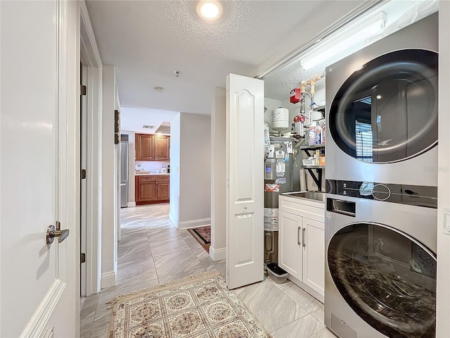 laundry room featuring cabinets, stacked washing maching and dryer, and a textured ceiling