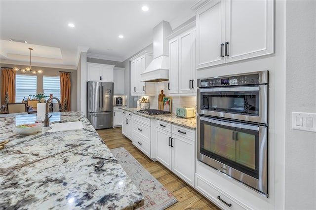 kitchen featuring white cabinetry, sink, light hardwood / wood-style floors, appliances with stainless steel finishes, and custom exhaust hood