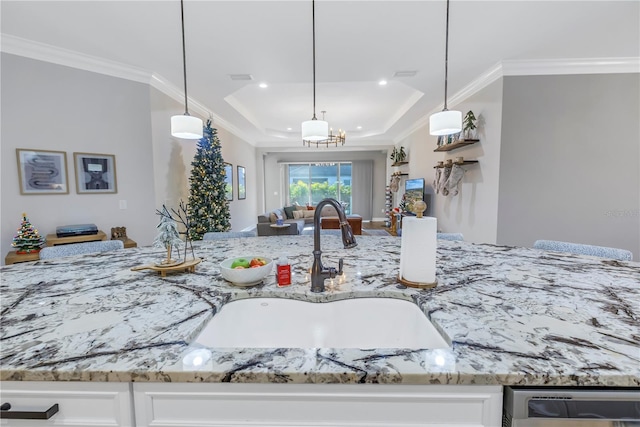 kitchen with sink, hanging light fixtures, light stone counters, white cabinets, and ornamental molding