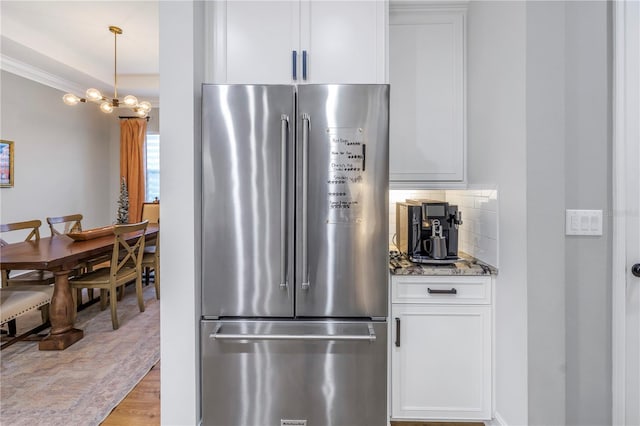 kitchen with white cabinetry, light hardwood / wood-style flooring, backsplash, dark stone countertops, and stainless steel fridge