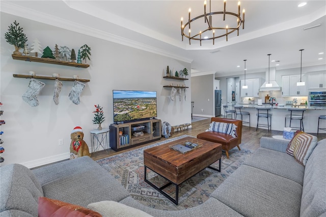 living room featuring light hardwood / wood-style floors, a raised ceiling, crown molding, and a chandelier