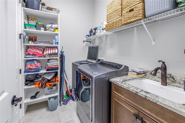 laundry area with washer and clothes dryer, sink, light tile patterned floors, and cabinets