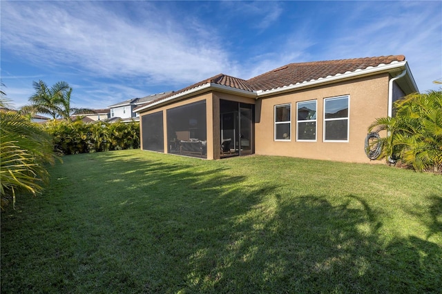 back of property with a sunroom and a yard