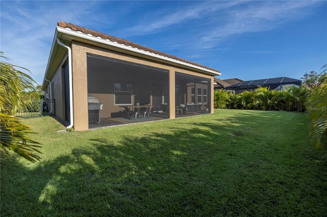 rear view of house with a sunroom and a lawn