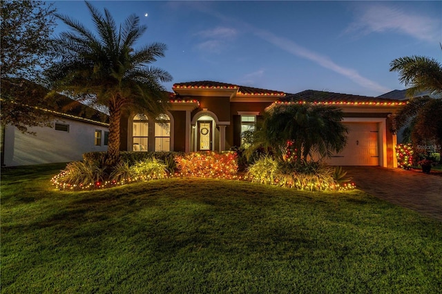 mediterranean / spanish-style house with a lawn and a garage