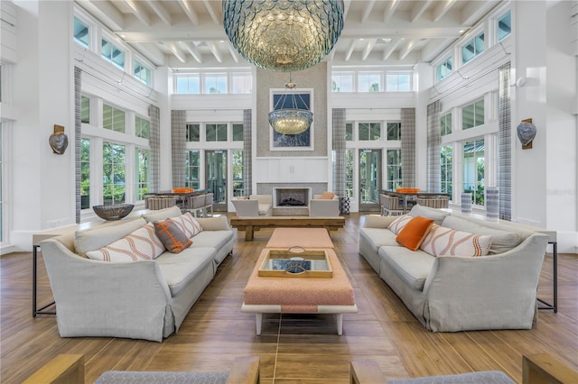 sunroom / solarium featuring beam ceiling, a wealth of natural light, a large fireplace, and a notable chandelier