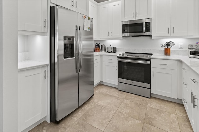 kitchen with light stone countertops, stainless steel appliances, and white cabinetry