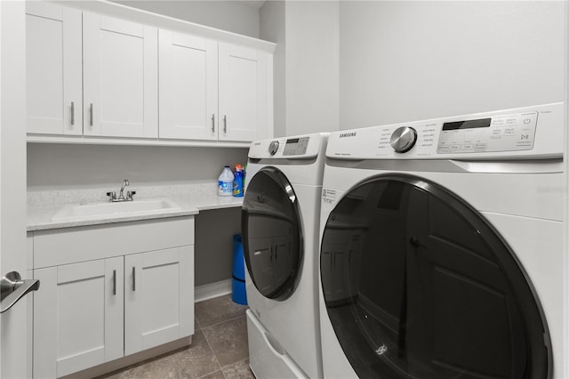 laundry room with washer and clothes dryer, cabinets, dark tile patterned flooring, and sink