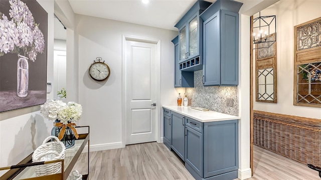 kitchen with blue cabinetry, light hardwood / wood-style floors, and tasteful backsplash