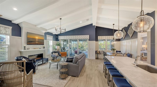 living room with a healthy amount of sunlight, light wood-type flooring, sink, and an inviting chandelier