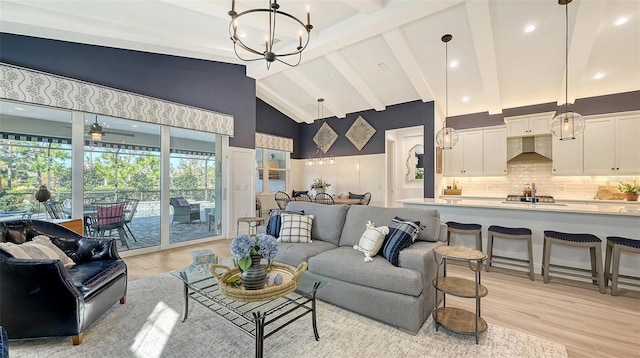 living room with ceiling fan with notable chandelier, beam ceiling, high vaulted ceiling, and light hardwood / wood-style flooring