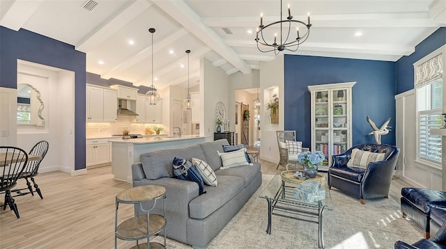 living room with vaulted ceiling with beams, a chandelier, and light hardwood / wood-style flooring