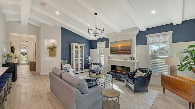 living room with plenty of natural light, light hardwood / wood-style floors, a tile fireplace, and a chandelier