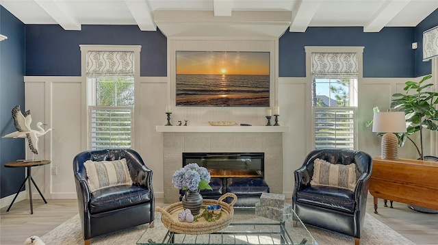 sitting room with beamed ceiling, a fireplace, and light hardwood / wood-style flooring