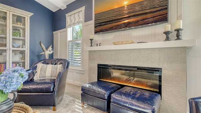 sitting room featuring a tile fireplace, light hardwood / wood-style floors, and vaulted ceiling