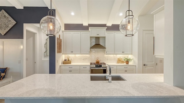 kitchen featuring white cabinets, wall chimney exhaust hood, sink, decorative light fixtures, and beamed ceiling