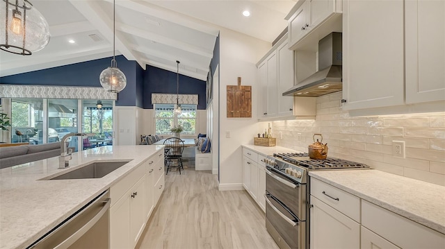 kitchen featuring sink, hanging light fixtures, vaulted ceiling with beams, wall chimney exhaust hood, and stainless steel appliances