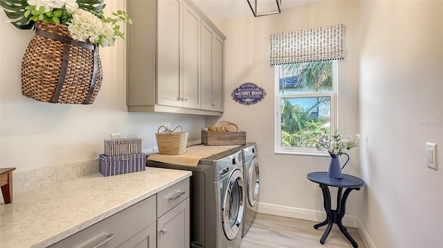 clothes washing area with separate washer and dryer and cabinets