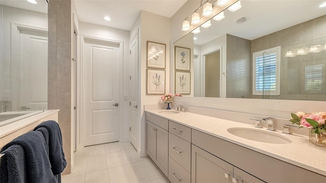 bathroom featuring tile patterned flooring, vanity, and a tile shower