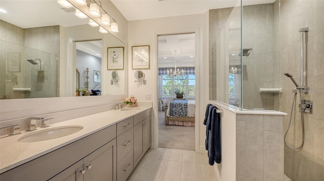 bathroom featuring tile patterned flooring, a tile shower, vanity, and a chandelier