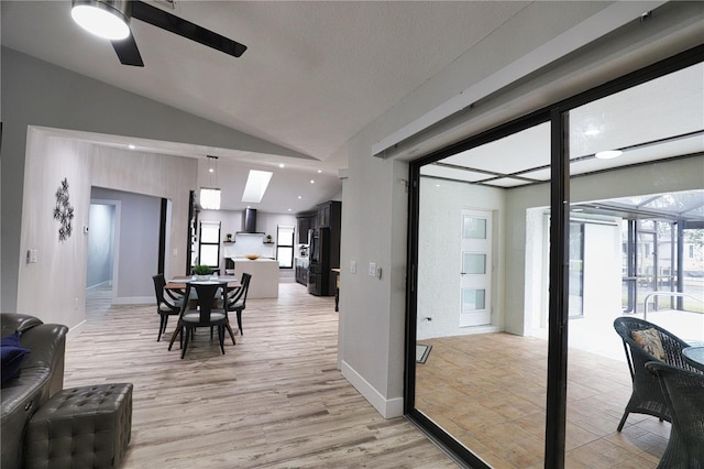 dining area featuring ceiling fan, vaulted ceiling, and light wood-type flooring