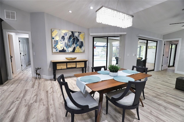 dining area featuring ceiling fan with notable chandelier, light hardwood / wood-style flooring, and lofted ceiling