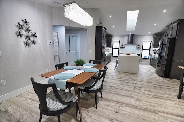 dining space with a skylight, light hardwood / wood-style floors, and a notable chandelier