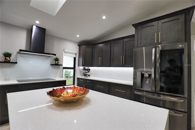 kitchen featuring light stone countertops, wall chimney exhaust hood, stainless steel fridge with ice dispenser, vaulted ceiling, and black electric cooktop