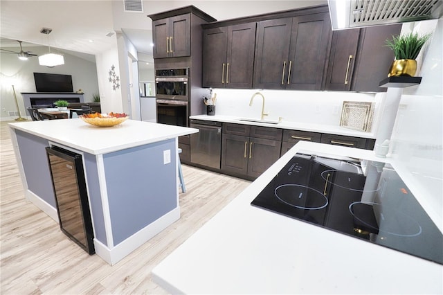 kitchen with dark brown cabinetry, ceiling fan, beverage cooler, sink, and black appliances