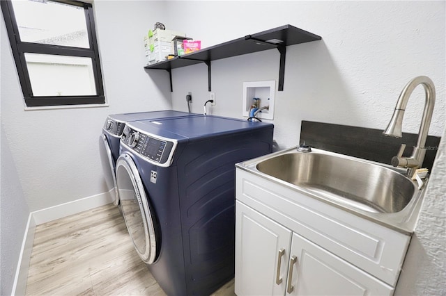 clothes washing area featuring cabinets, sink, light hardwood / wood-style flooring, and independent washer and dryer