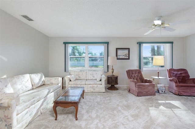 carpeted living room with ceiling fan and a textured ceiling