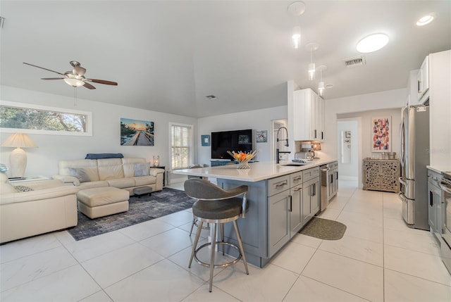 kitchen featuring sink, gray cabinets, appliances with stainless steel finishes, a kitchen bar, and white cabinetry