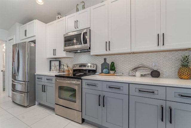 kitchen with lofted ceiling, backsplash, gray cabinets, white cabinetry, and stainless steel appliances