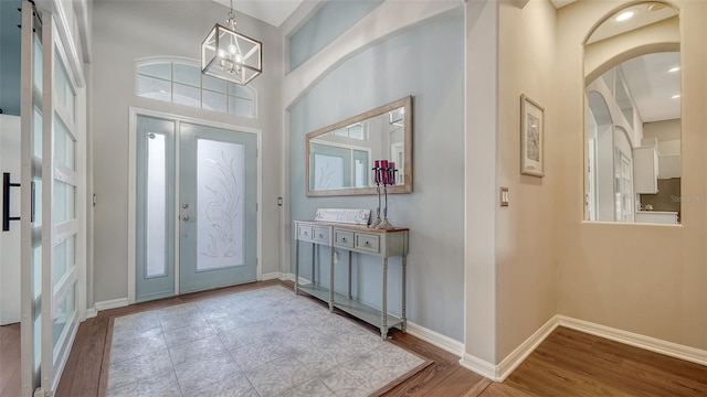 foyer entrance with a high ceiling, an inviting chandelier, and light hardwood / wood-style flooring