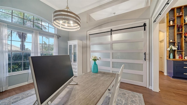 home office with a barn door, light hardwood / wood-style flooring, ornamental molding, and a notable chandelier